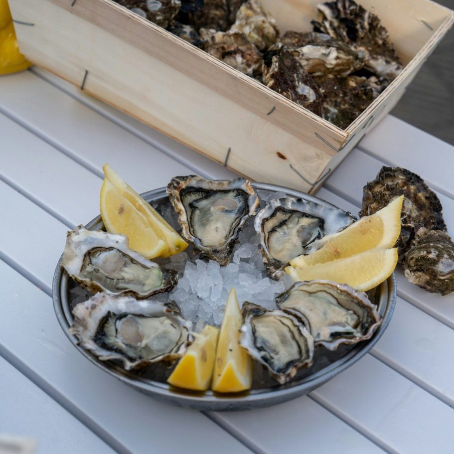 Assiette d'huitres fraîches avec quartiers de citron sur un lit de glace.